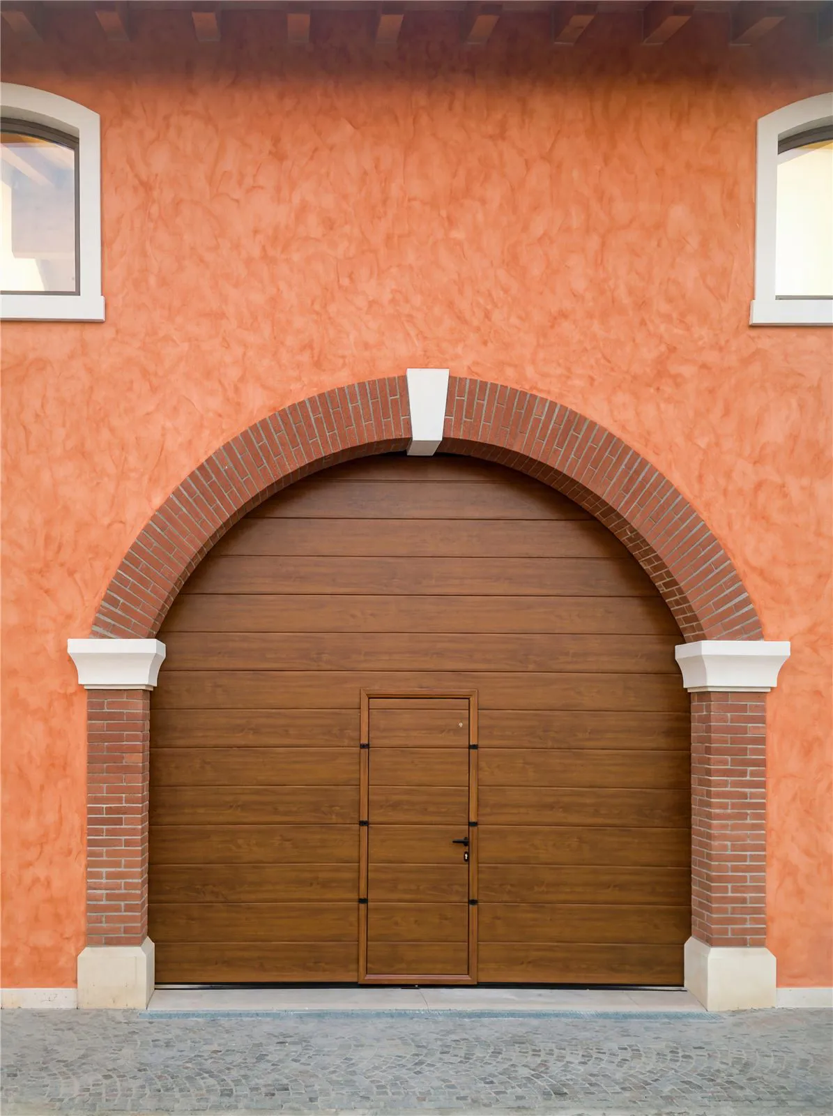 Portone sezionale effetto legno ad arco con porta pedonale
